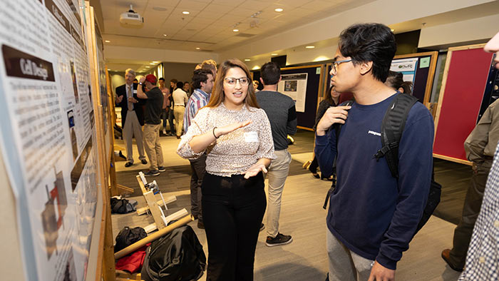 Ana Torres explaining her research poster to two students during the 2022 CNAS Undergraduate Research Symposium.