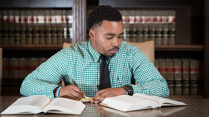 Criminology major Brandon Hill taking notes and reading from textbooks. 