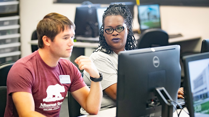 Nicole Allmondjoy talking to classmate in computer lab.